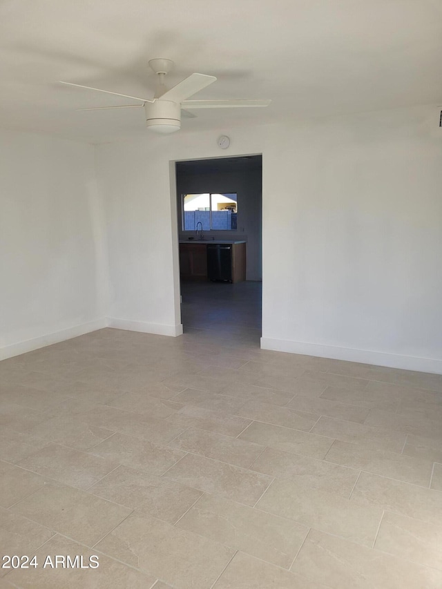 tiled spare room featuring ceiling fan and sink