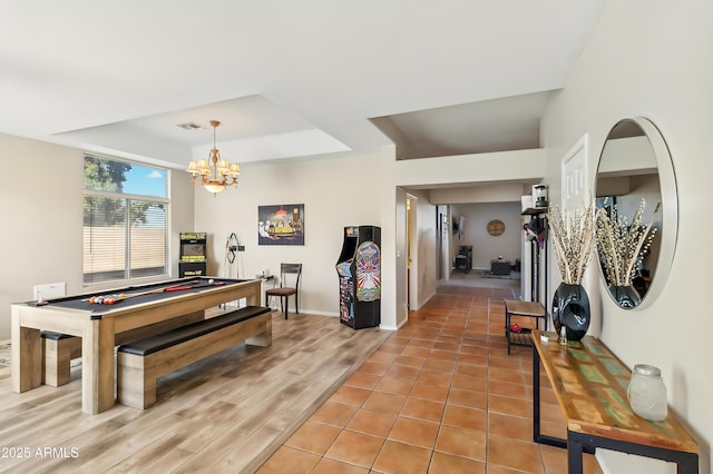 rec room with hardwood / wood-style flooring, a chandelier, and a raised ceiling