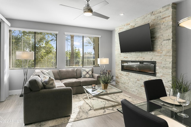 7700 E Gainey Ranch Rd Unit 206, Scottsdale, AZ 85258 - living area featuring ceiling fan, light wood finished floors, a stone fireplace, and baseboards