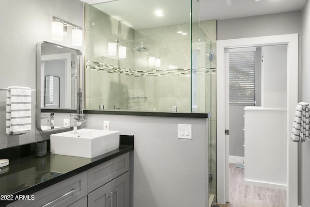 7700 E Gainey Ranch Rd Unit 206, Scottsdale, AZ 85258 - bathroom featuring a shower stall, double vanity, and wood finished floors