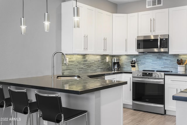 7700 E Gainey Ranch Rd Unit 206, Scottsdale, AZ 85258 - kitchen featuring appliances with stainless steel finishes, dark countertops, a sink, and a peninsula