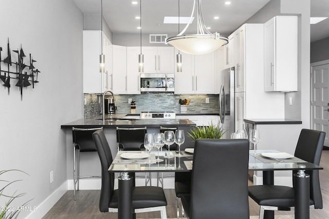 7700 E Gainey Ranch Rd Unit 206, Scottsdale, AZ 85258 - kitchen featuring appliances with stainless steel finishes, dark wood-style flooring, a sink, backsplash, and dark countertops