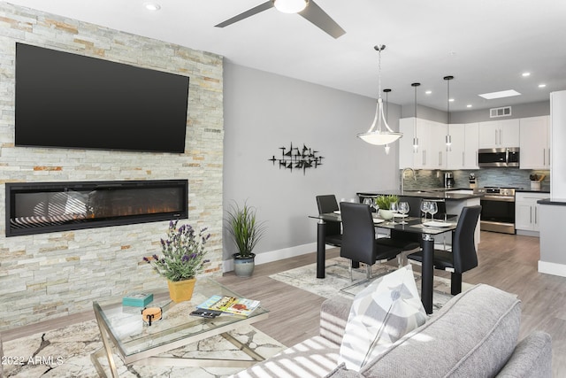 7700 E Gainey Ranch Rd Unit 206, Scottsdale, AZ 85258 - living area with light wood-style floors, ceiling fan, a stone fireplace, baseboards, and recessed lighting