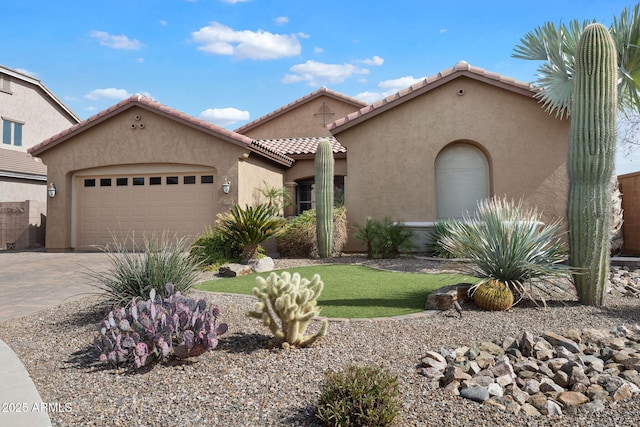 mediterranean / spanish-style house featuring decorative driveway, a tiled roof, an attached garage, and stucco siding