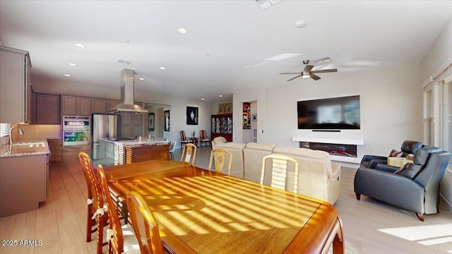 dining area with sink, ceiling fan, and light wood-type flooring