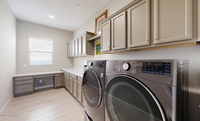 laundry room featuring cabinets, light wood-type flooring, and washer and clothes dryer