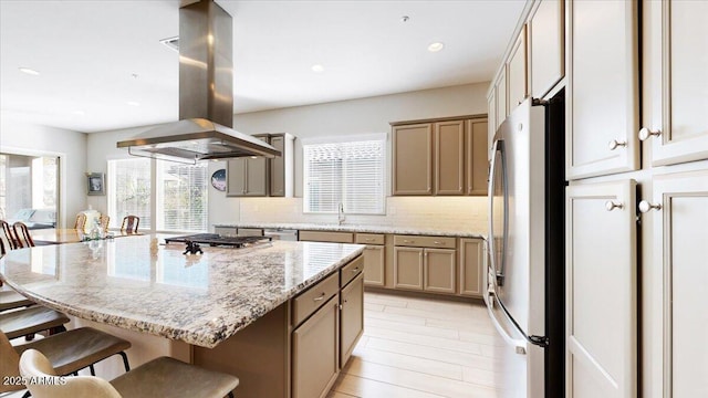 kitchen with stainless steel appliances, a center island, tasteful backsplash, island range hood, and a kitchen bar