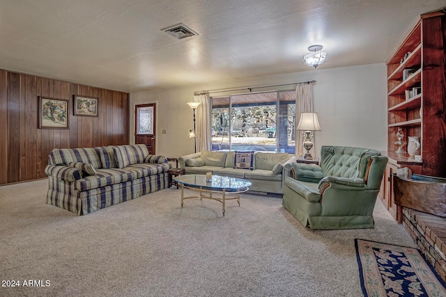 carpeted living room with a textured ceiling and wooden walls