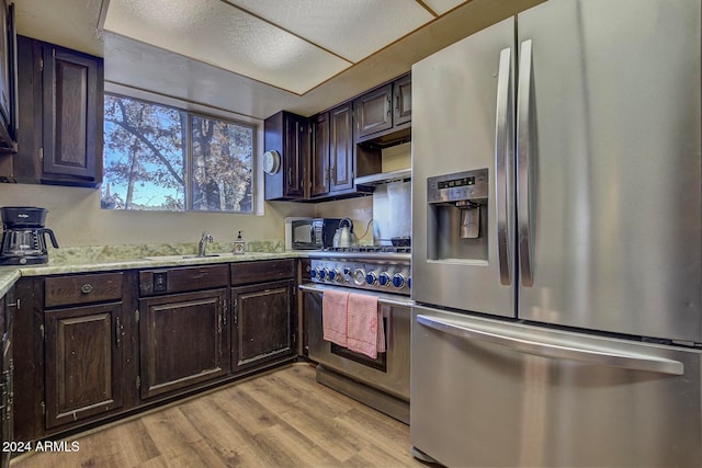 kitchen with sink, dark brown cabinets, light hardwood / wood-style floors, and appliances with stainless steel finishes