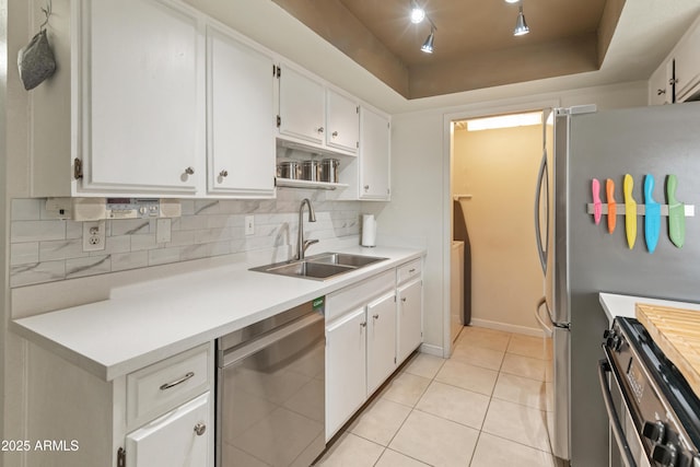 kitchen with light tile patterned floors, appliances with stainless steel finishes, white cabinetry, a raised ceiling, and a sink