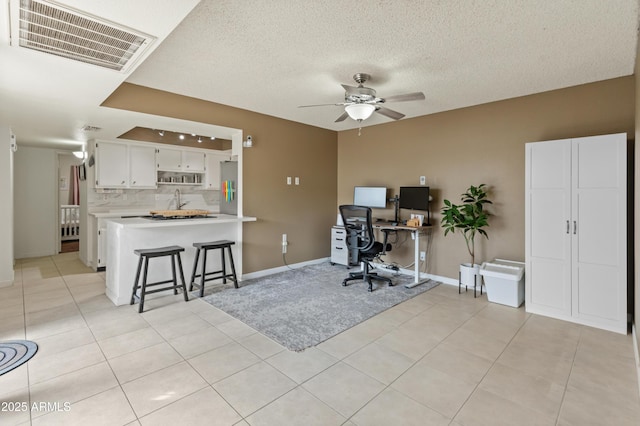 office area featuring light tile patterned floors, visible vents, a textured ceiling, and a ceiling fan