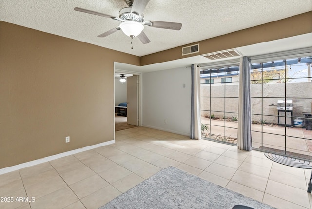 unfurnished room with tile patterned floors, visible vents, a textured ceiling, and a ceiling fan