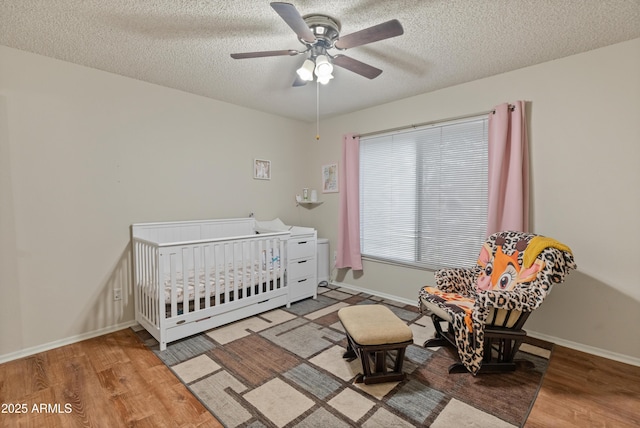 bedroom with a textured ceiling, baseboards, and wood finished floors