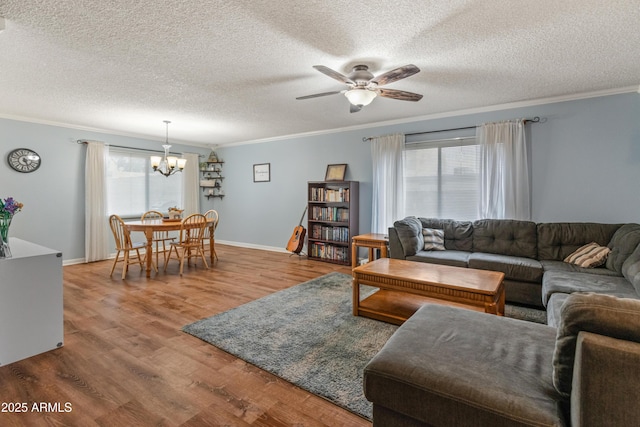 living area featuring baseboards, wood finished floors, crown molding, and ceiling fan with notable chandelier