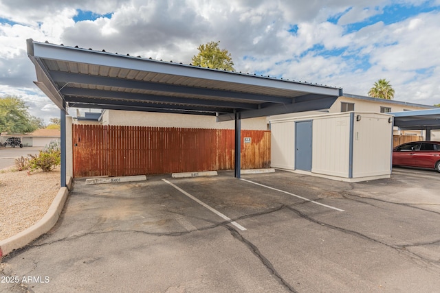 covered parking lot featuring a storage shed and fence