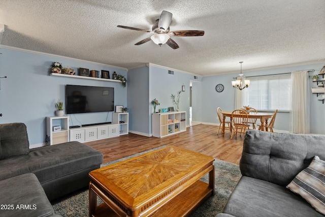 living area featuring ornamental molding, ceiling fan with notable chandelier, a textured ceiling, wood finished floors, and baseboards