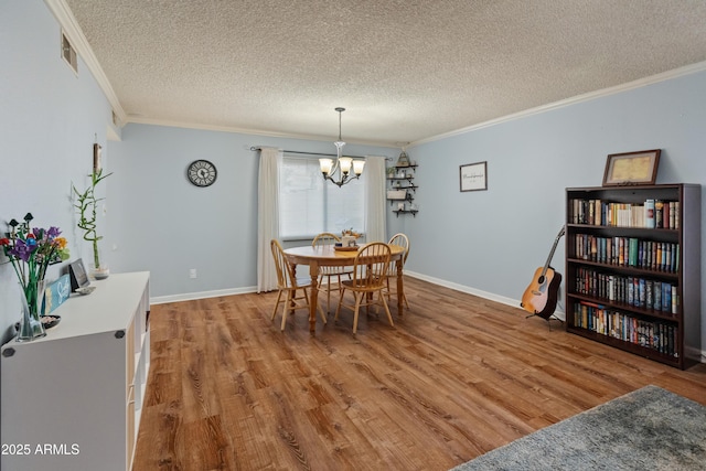 dining room with visible vents, crown molding, an inviting chandelier, wood finished floors, and a textured ceiling