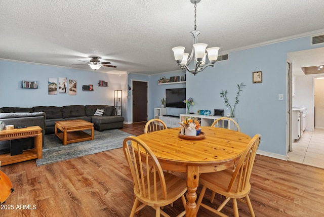 dining area featuring a textured ceiling, light wood-style floors, ornamental molding, and ceiling fan with notable chandelier