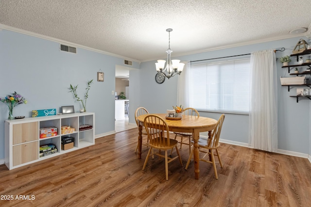 dining room with visible vents, a notable chandelier, wood finished floors, and crown molding