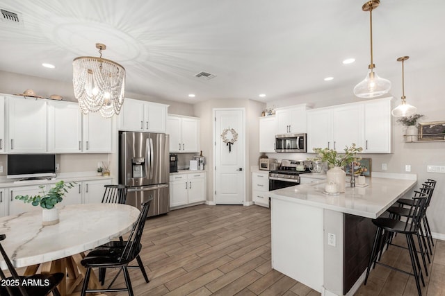 11526 E Shepperd Ave, Mesa, AZ 85212 - kitchen with appliances with stainless steel finishes, a peninsula, a kitchen bar, white cabinets, and recessed lighting