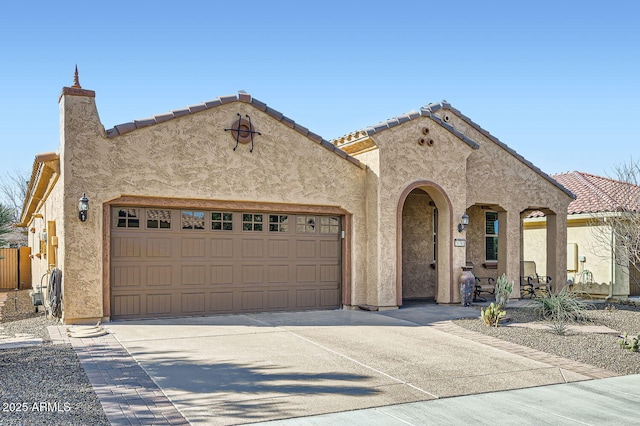 view of front of home featuring a garage, concrete driveway, a tiled roof, and stucco siding