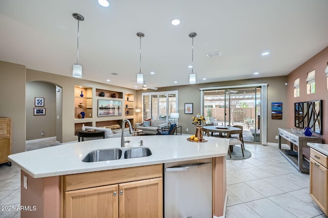 kitchen featuring open floor plan, a kitchen island with sink, a sink, and stainless steel dishwasher