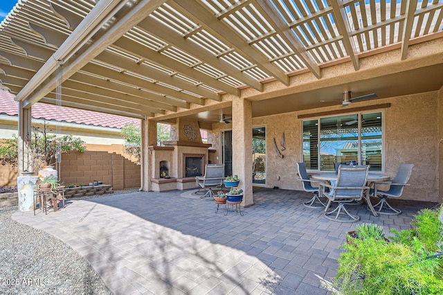 view of patio / terrace featuring ceiling fan, fence, exterior fireplace, a pergola, and outdoor dining space