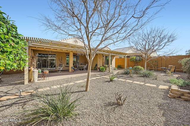 rear view of house featuring stucco siding, a patio area, fence, and a pergola