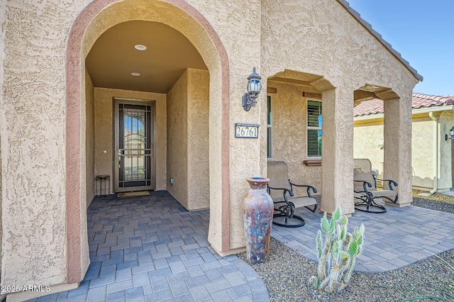 property entrance featuring a tile roof and stucco siding