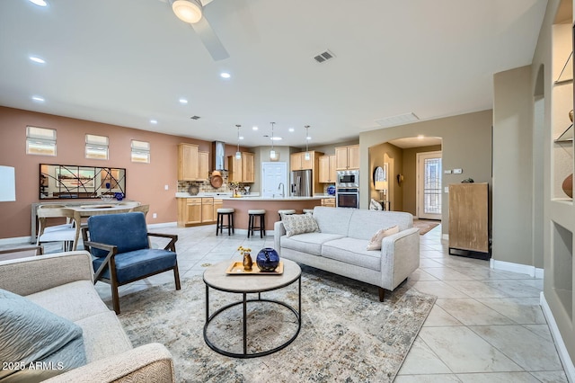 living area featuring arched walkways, baseboards, visible vents, and recessed lighting