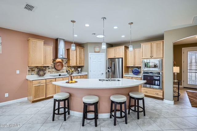 kitchen with wall chimney range hood, visible vents, stainless steel appliances, and light countertops