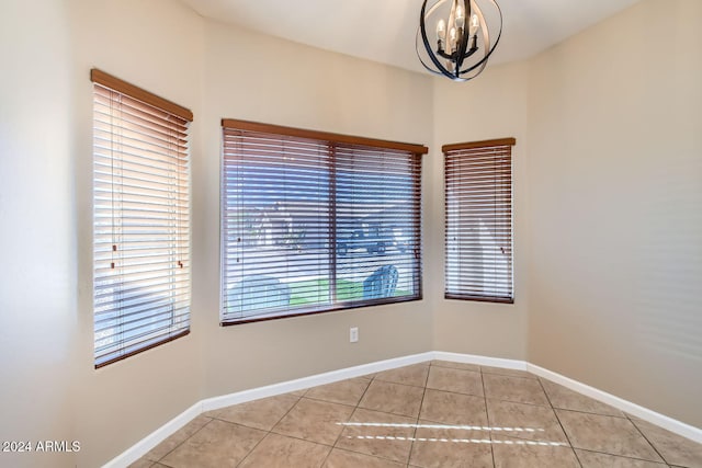 tiled empty room featuring an inviting chandelier