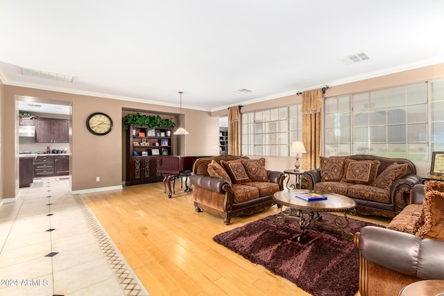 living area with light wood-style floors, visible vents, and crown molding