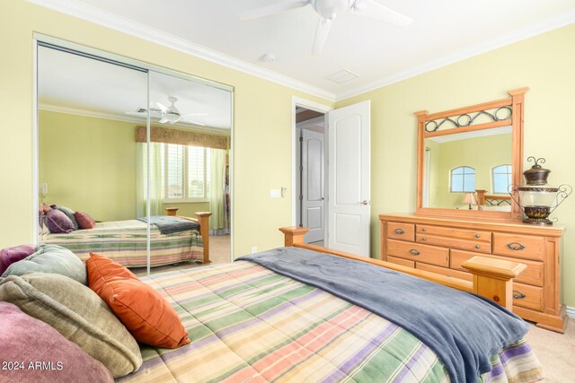 bedroom with light carpet, a closet, a ceiling fan, and crown molding