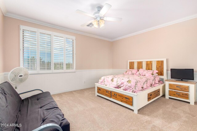 carpeted bedroom with ceiling fan, wainscoting, and crown molding