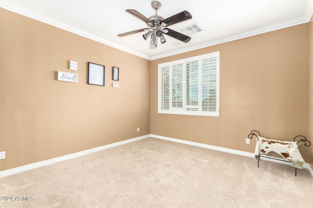 empty room with carpet, visible vents, crown molding, and ceiling fan