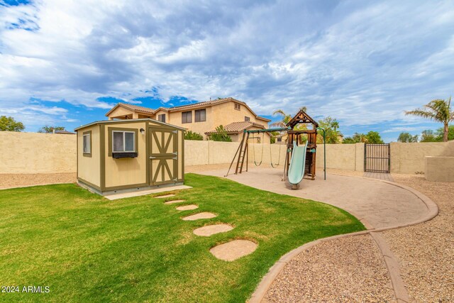 view of yard featuring an outbuilding, a storage unit, a playground, and a fenced backyard