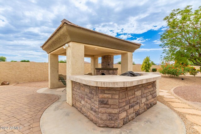 view of swimming pool featuring a jacuzzi, fence, a gazebo, a patio area, and an outdoor stone fireplace