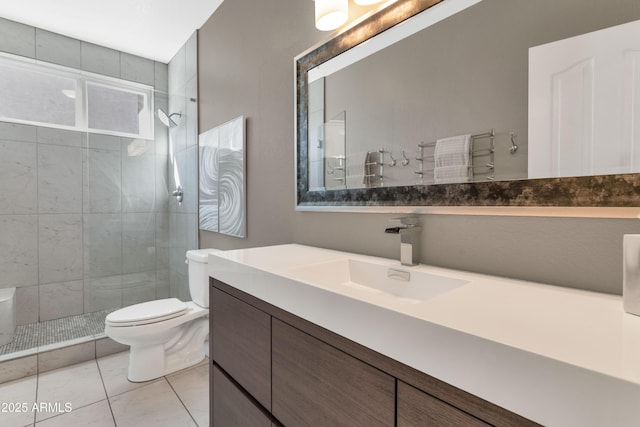 bathroom featuring vanity, toilet, tile patterned flooring, and a tile shower