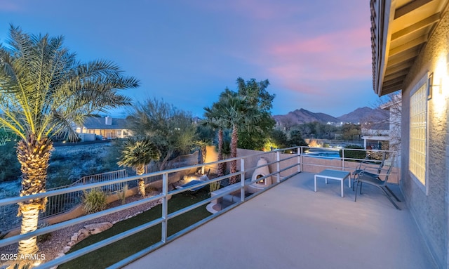 patio terrace at dusk featuring a balcony and a mountain view