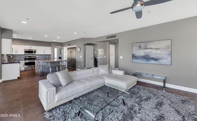 living room featuring ceiling fan, sink, and dark tile patterned floors