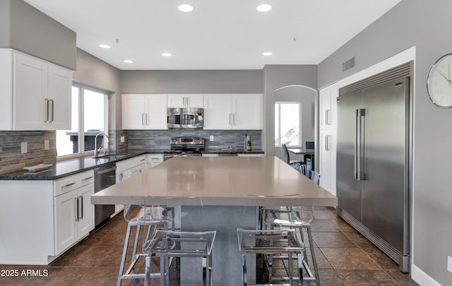 kitchen featuring plenty of natural light, a breakfast bar, white cabinets, and appliances with stainless steel finishes