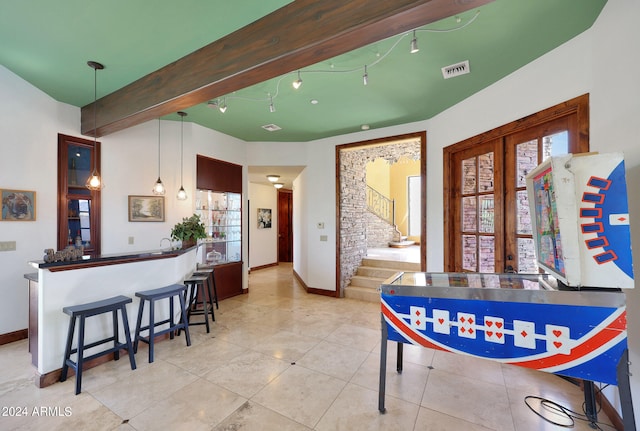 interior space featuring bar area, tile patterned flooring, beam ceiling, and french doors