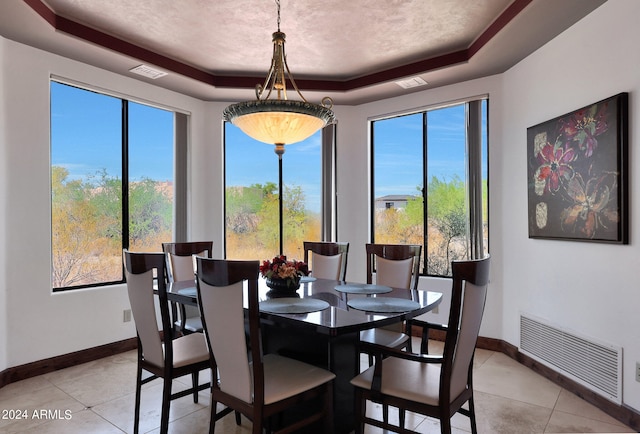 dining space featuring a tray ceiling, a healthy amount of sunlight, and light tile patterned flooring