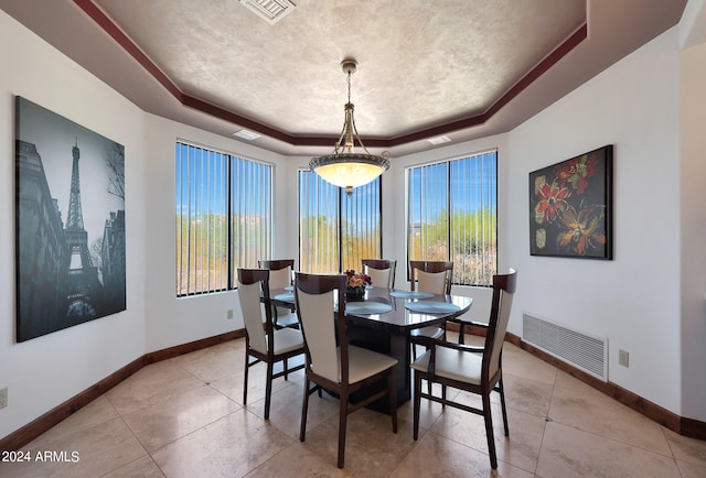 dining space with plenty of natural light and a raised ceiling