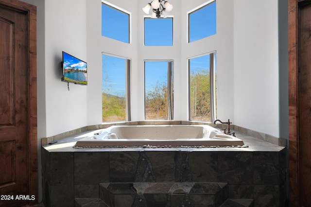 bathroom with a towering ceiling, a healthy amount of sunlight, and a tub