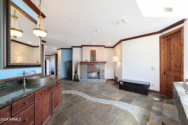 kitchen featuring crown molding, hanging light fixtures, sink, and a fireplace