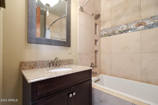 bathroom with tiled shower / bath combo and vanity