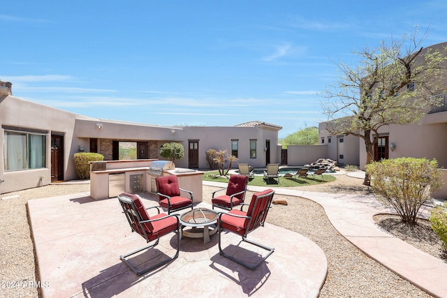 view of patio / terrace featuring exterior kitchen, grilling area, a fire pit, and a pool