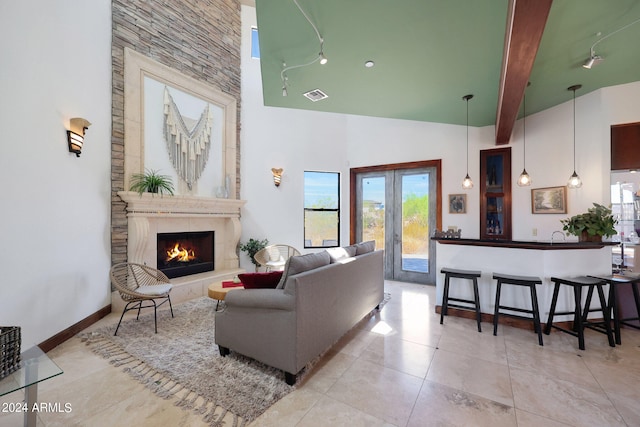 living room with a large fireplace, high vaulted ceiling, beamed ceiling, and french doors